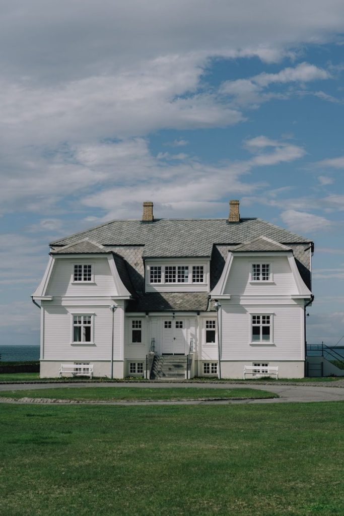 A large white house sitting on top of a lush green field